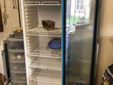 an open refrigerator in a kitchen with a bucket of paint on the floor