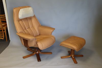 beige leather reclining chair with footstool and ottoman in front of a blue wall