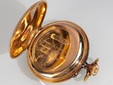 an antique gold pocket watch sitting on top of a white table