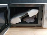 a microwave sitting on a wooden table with a bag in it