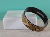 a close up of a black and gold bracelet on a table