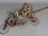 three wooden figurines of people riding on bicycles