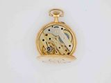 a gold pocket watch on a white surface with a white background