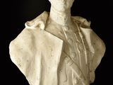 statue of a bust of a man wearing a suit and tie on a black background