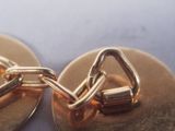 a close up of a pair of gold cufflinks on a table