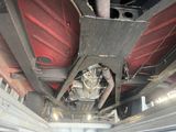 un homme qui se tient sous une voiture qui se trouve sous la voiture