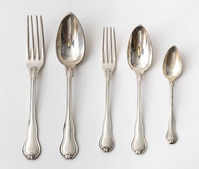 cinq cuillères en argent et une fourchette sont alignées sur une surface blanche