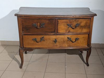 une commode en bois avec un plateau en marbre, posée sur un sol carrelé