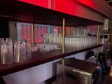 bottles and glasses on a shelf in a bar with a red light