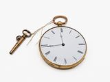 a pocket watch and a key on a white surface