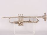 a silver trumpet on a clear stand with a white background