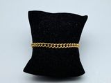 un oreiller noir sur lequel est posé un bracelet à chaîne dorée