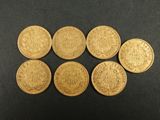 six souverains d'or britanniques alignés sur une surface noire