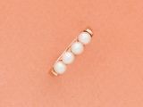 un gros plan d'une bague en or ornée de perles sur fond rose