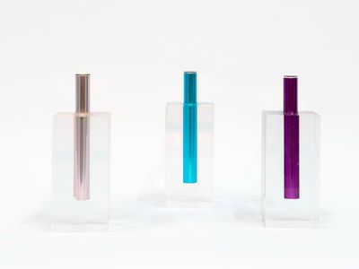 three different colored glass vases sitting side by side on a white surface