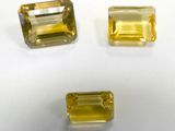 three yellow sapphires on a white surface