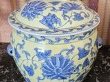 un vase jaune et bleu muni d'un couvercle, posé sur une table
