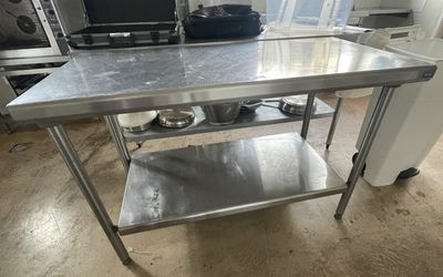 a stainless steel table in a kitchen with pots and pans on it