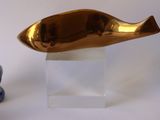 a gold fish sculpture next to a blue and white vase