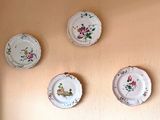 three plates on a wall with flowers on them hanging on the wall