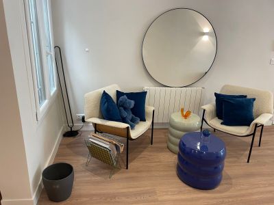un salon avec un canapé, des fauteuils et un miroir rond