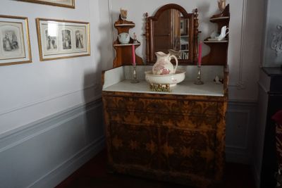 une commode sur laquelle est posé un bol, dans une pièce où il y a des tableaux accrochés au mur