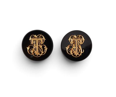 a pair of black and gold earrings with a monogram