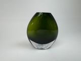un vase en verre vert posé sur une surface blanche