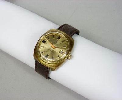 une montre en or posée sur une serviette blanche, sur une table blanche