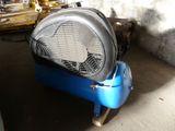 a blue air compressor sitting in a garage next to a wall