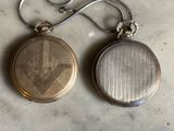 deux montres de poche en argent et en or posées sur une table