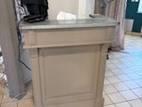 a small counter in the middle of a room with a lamp on it