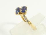 an image of a gold ring with two blue sapphires and diamonds