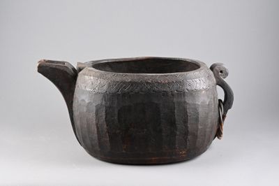 a black pot with a handle on a white surface