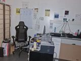 a room with a desk, chair, computer, and other items in it