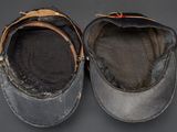 pair of black leather caps with brown leather straps on a gray surface