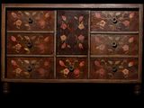 a wooden chest of drawers with flowers painted on it