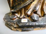 une statue représentant un homme coiffé d'un chapeau, assis sur un rocher