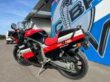 une moto rouge et noire garée devant un mur bleu et blanc