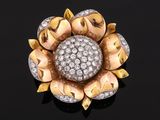 a gold and diamond flower broochle on a black surface