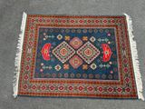 un gros plan d'un tapis posé sur une moquette, orné d'un motif rouge et bleu