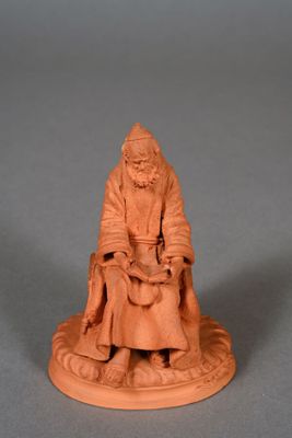 a small clay figurine of an old man sitting on a chair