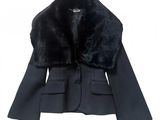 La veste est noire et est dotée d'un col en fourrure.