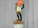 a statue of a man holding a lamp on top of a pedestal