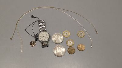 une montre en argent et quelques pièces de monnaie posées sur une table
