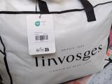a white bag with a tag on it sitting on a bed
