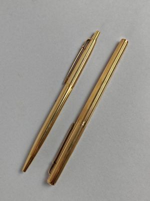 deux stylos dorés posés l'un sur l'autre sur une table