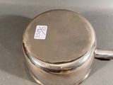a small silver pot with a handle on a table