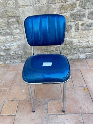 une chaise bleue posée devant un mur de pierre