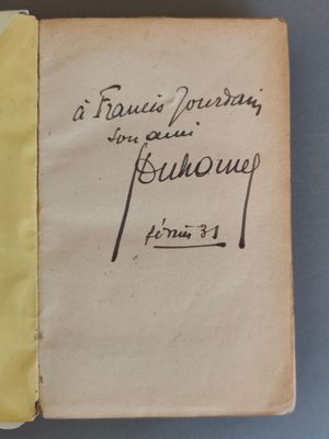 un vieux livre sur lequel on peut lire une inscription manuscrite, posé sur une table